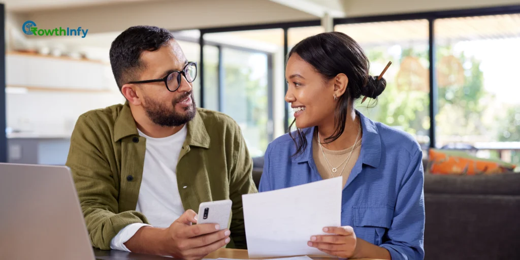 A couple sitting at a table with a laptop, discussing their budget and finances.


